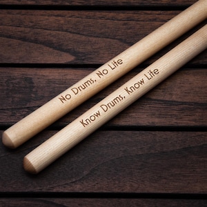May include: Two wooden drumsticks with the text "No Drums, No Life" and "Know Drums, Know Life" engraved on them.