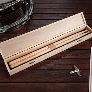 May include: A wooden box with a hinged lid, containing two wooden drumsticks. The drumsticks are engraved with the text "No Drum, No Life" and "Know Drum, Know Life".
