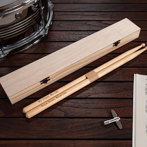 May include: A pair of wooden drumsticks in a wooden box with the inscription "No Drum, No Life. Know Drum, Know Life".