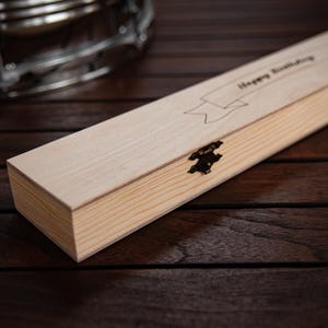 May include: A wooden box with a hinged lid and a brass clasp. The box is engraved with the words "Happy Birthday".