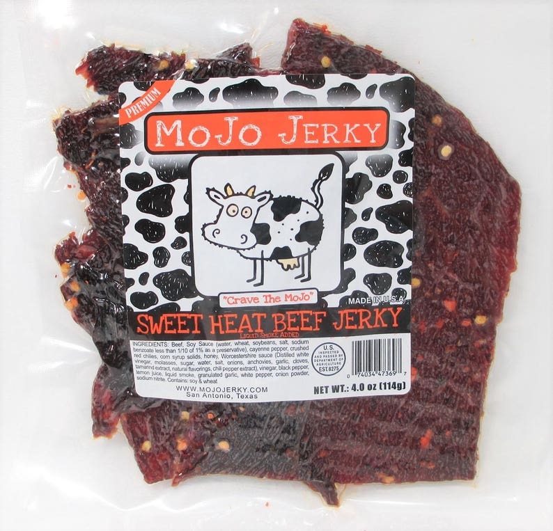 May include: A bag of Mojo Jerky Sweet Heat Beef Jerky, featuring a cartoon cow with the text "Crave The Mojo" and a black and white cow print background. The bag contains 4 ounces (114 grams) of jerky.