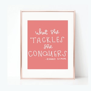 May include: A pink printable quote with white text that reads "What she tackles she conquers - Richard Gilmore".