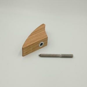 May include: A wooden furniture component with a curved shape, featuring a hexagonal bolt and a separate metal screw. The wood has a natural grain and light brown color. The screw is silver.