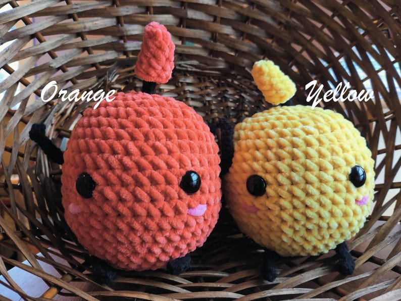 Peut inclure: Deux jouets en peluche crochet&eacute;s dans un panier en osier. Le jouet orange a un petit chapeau pointu et le jouet jaune a un chapeau arrondi. Les deux jouets ont des yeux noirs et des joues roses.