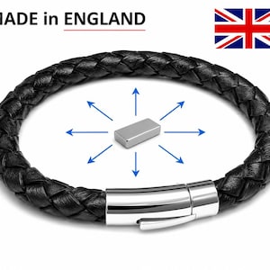 Op de afbeelding: Zwart gevlochten leren armband met een zilveren sluiting. Gemaakt in Engeland. De afbeelding toont een zilveren rechthoekig object in het midden met blauwe pijlen die naar buiten wijzen.