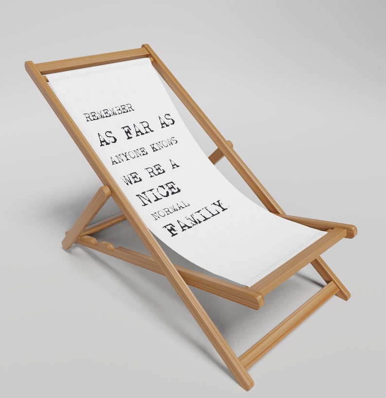May include: A white canvas deckchair with a wooden frame. The chair has a black and white text print that reads "Remember as far as anyone knows we're a nice normal family."