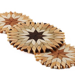 May include: Three round wooden coasters with a starburst design in shades of brown, beige, and white. The coasters are made of wood and have a beaded edge.