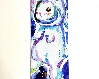 May include: A watercolour illustration of a white rabbit wearing an astronaut suit floating in space. The background is a dark blue with white stars.