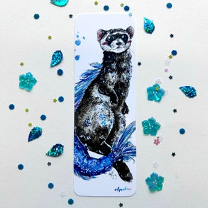 May include: A bookmark featuring a watercolor illustration of a ferret with a mermaid tail. The ferret is black and white with a blue and white tail. The background is white with blue bubbles. The bookmark is signed "Aquaferret" and dated "Aug 23".