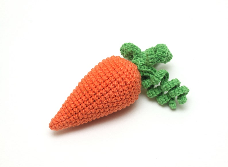 May include: A crocheted carrot toy with a green leafy top. The carrot is orange and the leaves are green.
