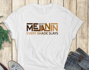 May include: White t-shirt with the text "MADE WITH MELANIN EVERY SHADE SLAYS" in brown and black lettering.