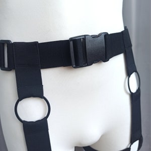 K&ouml;nnte beinhalten: Schwarzer verstellbarer Strumpfbandhalter mit zwei Beinschlaufen und einem Schnallenverschluss.