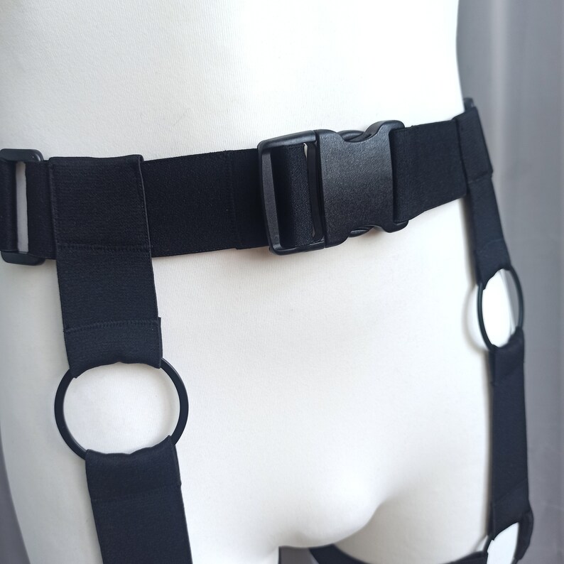 K&ouml;nnte beinhalten: Schwarzer verstellbarer Strumpfbandhalter mit zwei Beinschlaufen und einem Schnallenverschluss.