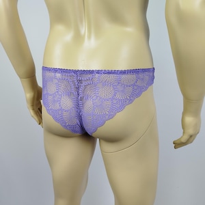 Puede incluir: Un par de ropa interior de encaje lavanda. La ropa interior se muestra en un maniquí. El diseño de encaje es intrincado, con un borde festoneado a lo largo de la cintura y las aberturas de las piernas. El color es un púrpura suave y apagado.