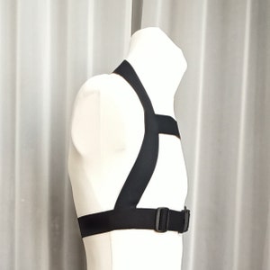 May include: A black adjustable harness with a buckle closure. The harness is made of a soft, flexible material and has a comfortable fit.
