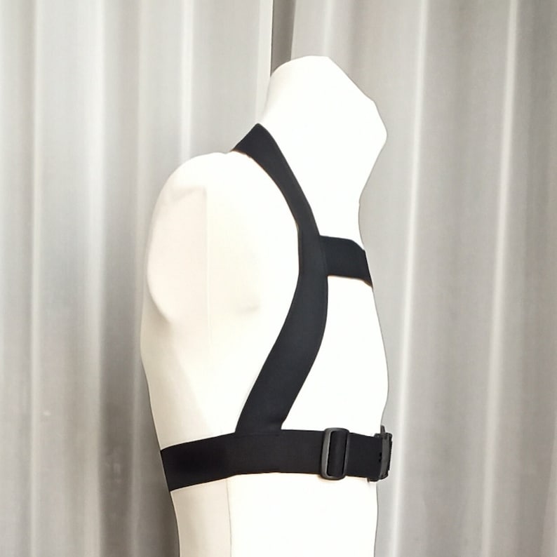 May include: A black adjustable harness with a buckle closure. The harness is made of a soft, flexible material and has a comfortable fit.