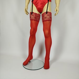 Può includere: Calze rosse alte fino alla coscia con bordo in pizzo floreale, esposte su un manichino. Le calze sono abbinate a uno slip in raso rosso e a un reggicalze con spalline nere. Il manichino è su una base rotonda trasparente.