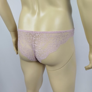 Puede incluir: Ropa interior de encaje lavanda pálido. El delicado diseño floral de encaje cubre la parte delantera y trasera de la prenda. Los bordes están acabados con un ribete festoneado. La ropa interior se muestra en un maniquí.