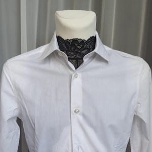 Pode incluir: Uma camisa branca com uma gola de renda preta.