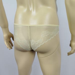 Puede incluir: Ropa interior amarillo pálido con ribete de encaje floral. La tela transparente revela la forma de la prenda. El ribete de encaje es de un tono amarillo más claro y añade un toque delicado al diseño.