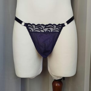Può includere: Lingerie in pizzo di colore viola scuro con un delicato motivo floreale. La lingerie ha spalline regolabili e un delicato bordo.