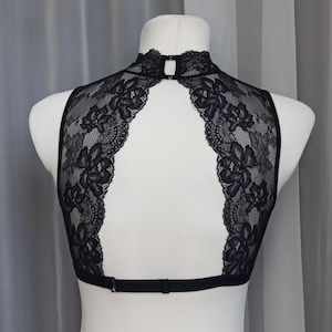 Pode incluir: Bralette de renda preta com decote alto e costas baixas. A bralette tem al&ccedil;as ajust&aacute;veis e fecho de gancho e olho.
