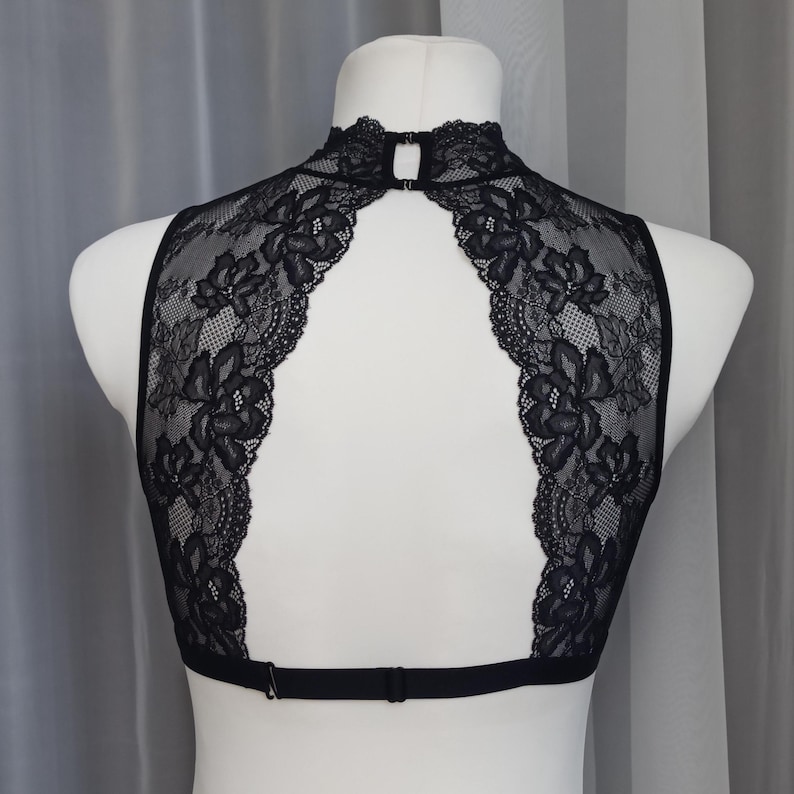 Pode incluir: Bralette de renda preta com decote alto e costas baixas. A bralette tem al&ccedil;as ajust&aacute;veis e fecho de gancho e olho.