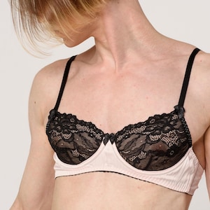 May include: A black lace bra with a pink satin trim. The bra has adjustable straps and a hook and eye closure in the back.