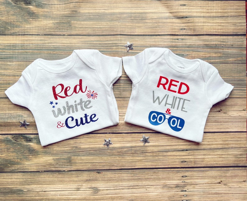 May include: Two white baby onesies with red, white, and blue text. One onesie says "Red white & Cute" with a firework graphic. The other onesie says "Red white & Cool" with a graphic of sunglasses.