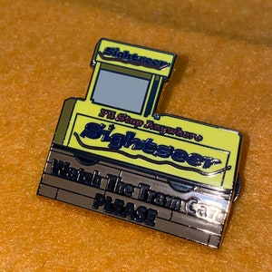 Puede incluir: Pin amarillo y plateado con forma de vag&oacute;n de tren. El pin tiene la palabra "Sightseer" y el texto "I'll Stop Anywhere" y "Watch The Train Car PLEASE".