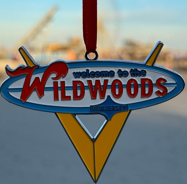 May include: A blue and yellow metal ornament shaped like a surfboard with the words "Welcome to the Wildwoods, New Jersey" in red and white lettering.