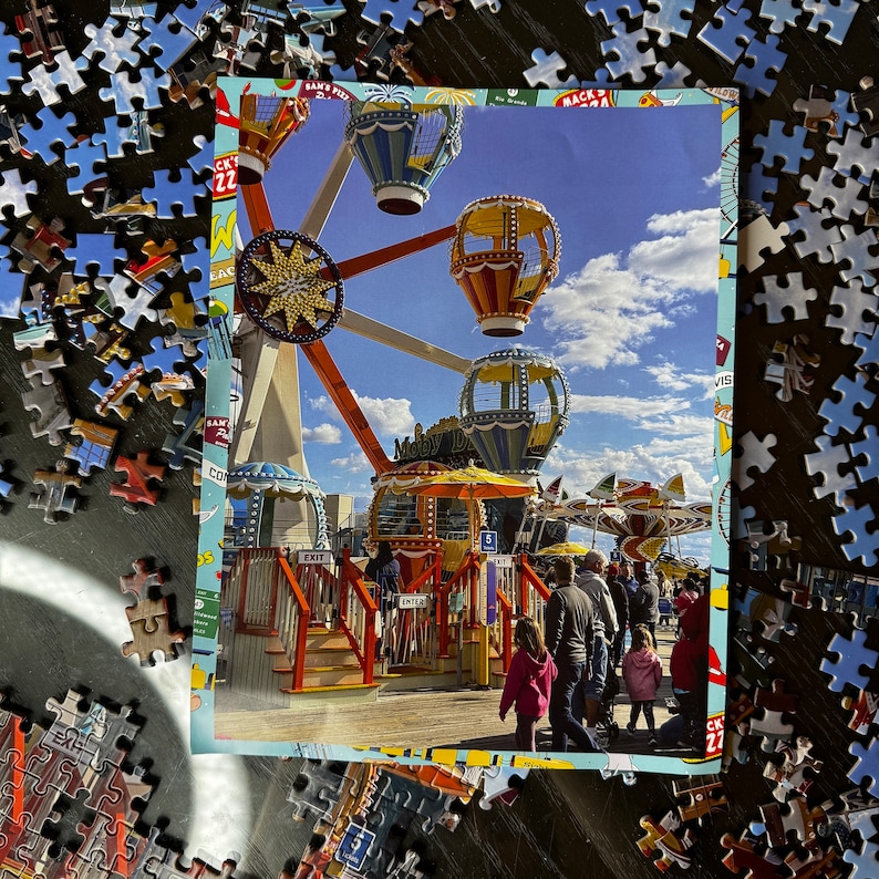 May include: A colorful carnival ride with a Ferris wheel, a carousel, and a swing ride. The ride is decorated with bright colors and lights. The ride is set against a blue sky with white clouds.