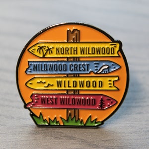 Pu&ograve; includere: Una spilla smaltata colorata con un cartello di legno con quattro frecce direzionali. Le frecce indicano "North Wildwood", "Wildwood Crest", "Wildwood" e "West Wildwood".
