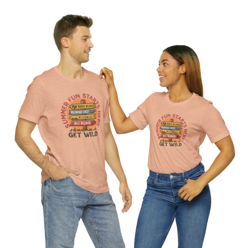 Pu&ograve; includere: Due magliette color pesca con la scritta "SUMMER FUN STARTS HERE" e "GET WILD" stampata. Il design include segnali direzionali che puntano a vari luoghi. Le magliette sono indossate da due persone.