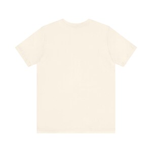 May include: A cream-colored, short-sleeved t-shirt. The shirt has a crew neck and a relaxed fit. The fabric appears to be soft and lightweight, suitable for casual wear. The t-shirt is a solid color with no visible graphics or patterns.