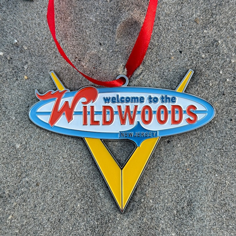 May include: A yellow, blue, and red metal ornament shaped like a surfboard with the text "Welcome to the Wildwoods New Jersey".