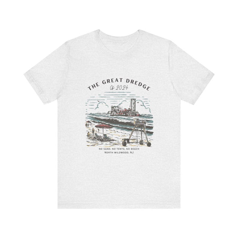 May include: A light gray t-shirt featuring a graphic of a beach scene with a dredge, waves, and a lifeguard stand. Text on the shirt reads "THE GREAT DREDGE of 2024" and "NO SAND. NO TENTS. NO BEACH. NORTH WILDWOOD, NJ."