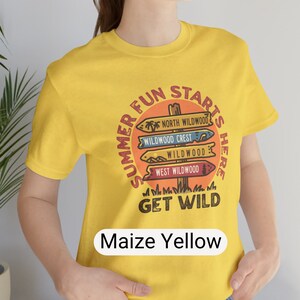 Pu&ograve; includere: T-shirt giallo mais con grafica circolare con la scritta "Summer Fun Starts Here" e "Get Wild". La grafica presenta segnali direzionali per North Wildwood, Wildwood Crest e West Wildwood. La maglietta &egrave; a girocollo e maniche corte.