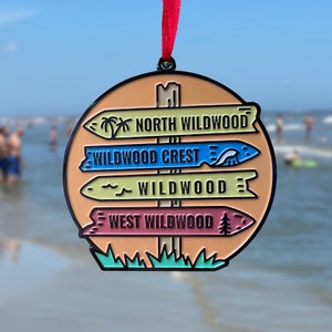 May include: A colorful metal signpost ornament with four directional signs. The signs read "North Wildwood", "Wildwood Crest", "Wildwood", and "West Wildwood".