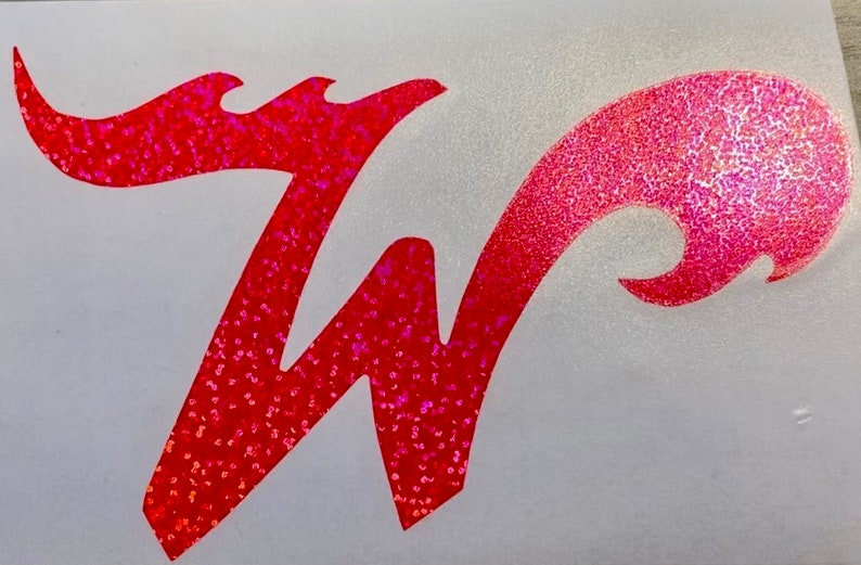 May include: A pink and red glitter vinyl decal of the letter "W" in a stylized font. The decal is on a white background.