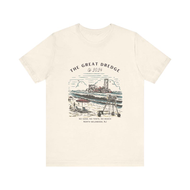 May include: Cream-colored t-shirt featuring a beach scene with the text "THE GREAT DREDGE OF 2024." The graphic includes a lifeguard stand, waves, and a dredging machine. Below the image, it reads "NO SAND, NO TENTS, NO BEACH NORTH WILDWOOD, NJ."