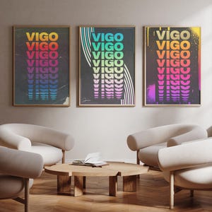 May include: Three framed art prints with the word "VIGO" in a repeating, colorful design. The prints are displayed above a seating area with curved, cream-colored chairs and a wooden coffee table. The room has a modern aesthetic.