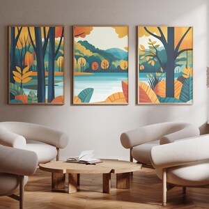 May include: Three framed abstract landscape prints with a blue lake, green trees, and yellow, orange, and brown foliage. The prints are hanging on a light beige wall above a wooden coffee table and three white armchairs.