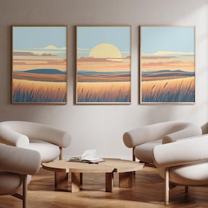 Puede incluir: Tres impresiones enmarcadas de paisajes con una puesta de sol sobre un campo de hierba. Las impresiones están colgadas en una pared de color beige claro en un salón con tres sillones blancos y una mesa de café de madera.