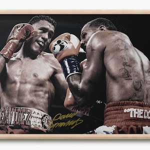 Può includere: Due pugili in un ring di boxe, uno indossa un uniforme da boxe marrone e arancione con il nome "HERNANDEZ" su di esso, l'altro indossa un uniforme da boxe marrone e bianco con il testo "THE DOG" su di esso. Il pugile a sinistra sta lanciando un pugno con la mano sinistra, mentre il pugile a destra sta bloccando il pugno con la mano destra. Il pugile a destra ha dei tatuaggi sulla schiena.