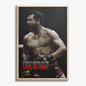 Puede incluir: Una foto en blanco y negro de un hombre sin camisa con barba, usando guantes de boxeo y pantalones cortos. El hombre está gritando y tiene una expresión decidida en su rostro. El texto "I'M NOT IN THIS FOR THE FAME I'M IN THIS SPORT BECAUSE I JUST LOVE TO FIGHT" está impreso en rojo y blanco en la imagen. La firma del hombre está en tinta negra debajo del texto.