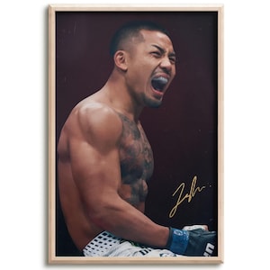 May include: A framed portrait of a shirtless fighter with a mouthguard, shouting with an intense expression. The fighter has visible chest and arm tattoos, wears white patterned shorts and black gloves, and features a gold signature on the print.