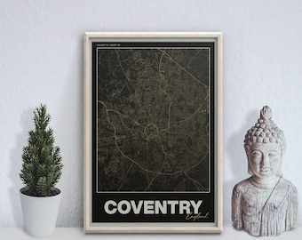 May include: Framed map print of Coventry, England, with a detailed street layout in gold against a black background. The city name is displayed in white block letters at the bottom, with "England" in script. A small potted plant and a Buddha statue are on either side.