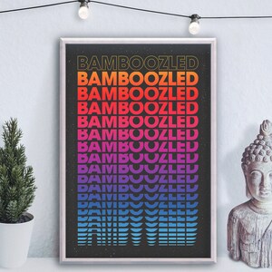 May include: A black and white poster with the word "BAMBOOZLED" repeated in a rainbow gradient pattern. The poster is framed in a white frame and hanging on a white wall.