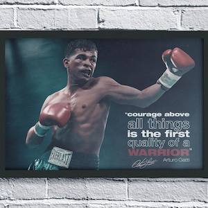 Op de afbeelding: Ingelijste print met een bokser in rode handschoenen, met de quote "moed boven alles is de eerste kwaliteit van een krijger" van Arturo Gatti. De bokser draagt een groene broek met het Everlast-logo.